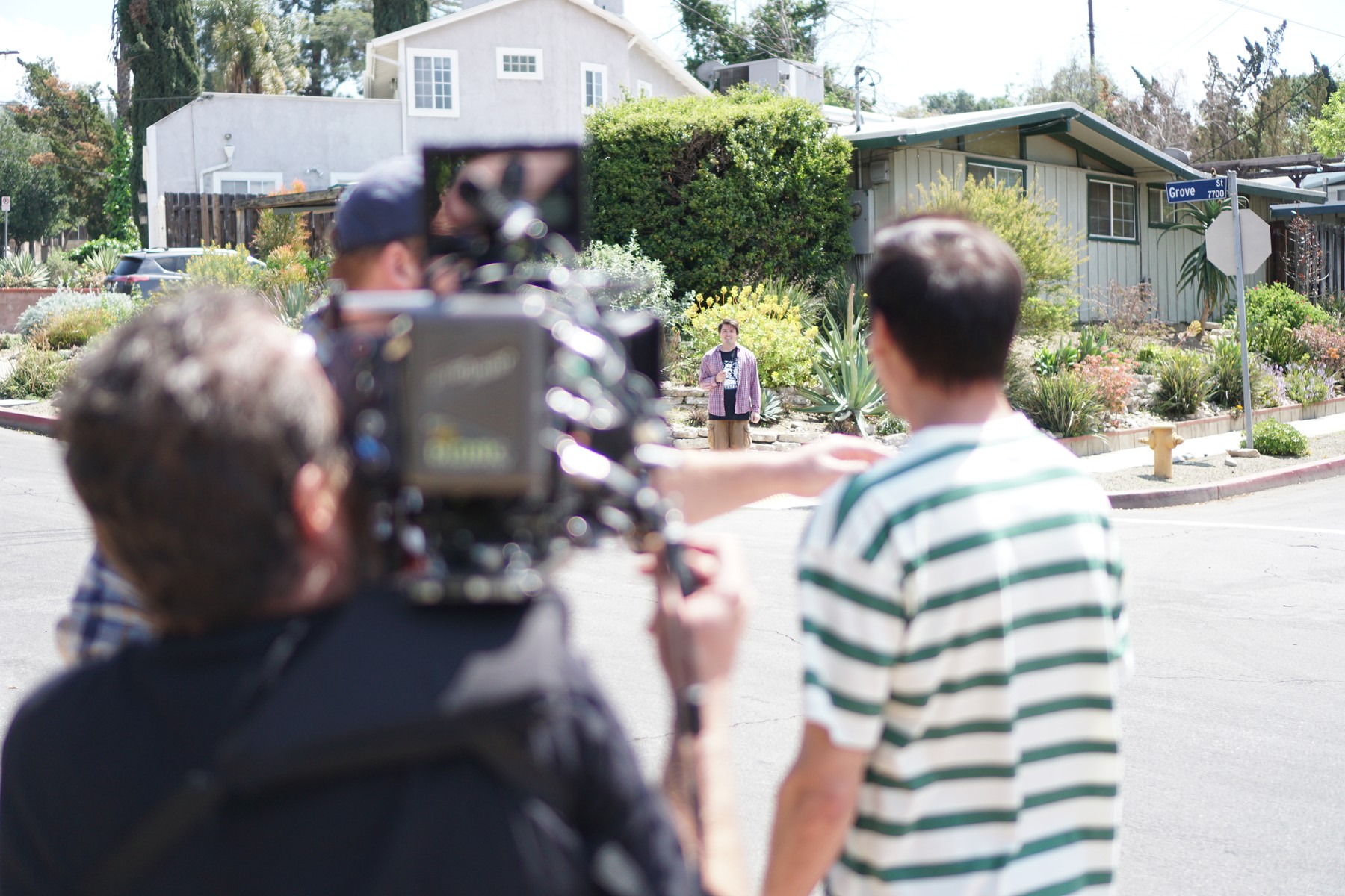 Camera crew filming a performer on a residential street