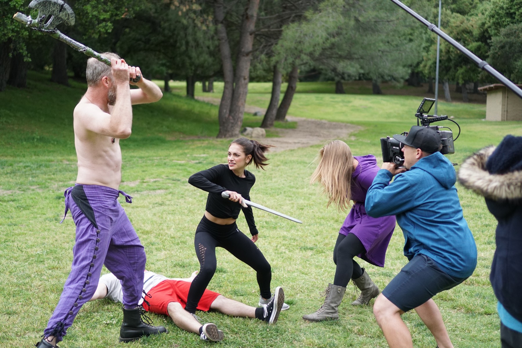 Cast and camera crew filming a practical fight scene in a park